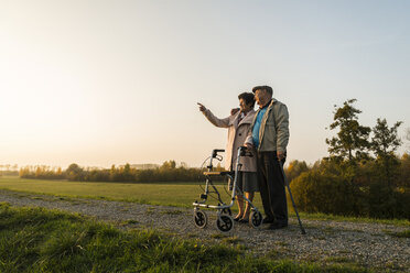 Älteres Paar mit Gehstock und Rollator in der Natur stehend - UUF006159