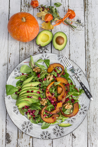 Autumnal salad with squash, pomegranate seeds, avocado and walnuts stock photo