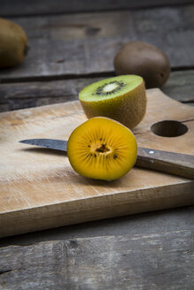 Grüne und goldene Kiwis auf Schneidebrett, Holz - LVF004172