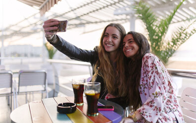 Zwei Freundinnen machen ein Selfie mit Smartphone in einem Café - MGOF001077