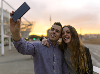 Junges Paar macht ein Selfie mit Smartphone in der Abenddämmerung - MGOF001083