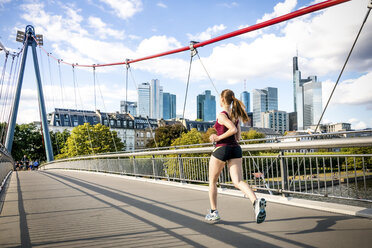 Germany, Frankfurt, young woman jogging on bridge - PUF000437