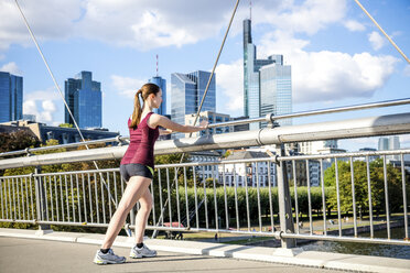 Deutschland, Frankfurt, junger Sportler beim Dehnen auf der Brücke - PUF000438