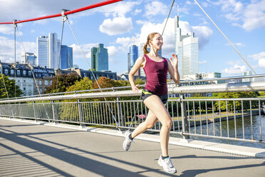 Deutschland, Frankfurt, junge Frau joggt auf Brücke - PUF000439