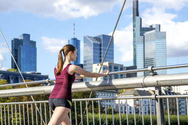 Deutschland, Frankfurt, junger Sportler beim Dehnen auf der Brücke - PUF000440