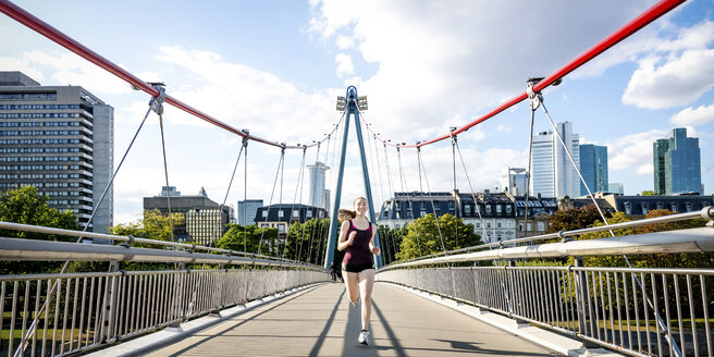 Germany, Frankfurt, young woman jogging on bridge - PUF000441