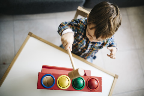 Kleiner Junge spielt mit Holzspielzeug für motorische Fähigkeiten, lizenzfreies Stockfoto