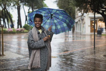 Italien, Grado, lächelnde Frau mit Regenschirm an einem regnerischen Tag im Herbst - MAUF000061