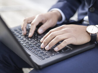 Germany, Cologne, Young businessman typing on laptop, close up - MADF000691