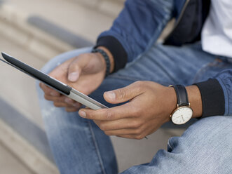 Deutschland, Köln, Junger Mann sitzt auf einer Bank und benutzt ein digitales Tablet - MADF000703