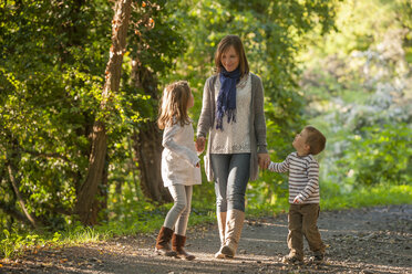 Mutter geht mit ihren Kindern auf einem Waldweg spazieren - PAF001476
