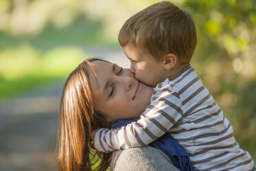 Little boy hugging and kissing his happy mother - PAF001477