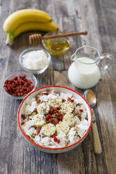 Bowl of muesli with banana slices, chia seeds, coconut chips and goji berries - SARF002325