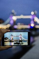 Großbritannien, London, Männerhand hält Smartphone mit Foto der Tower Bridge in der Dämmerung - MAUF000078