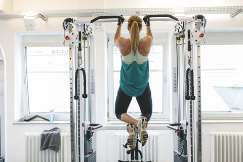 Frau macht Klimmzüge im Fitnessstudio, lizenzfreies Stockfoto