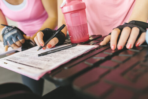 Nahaufnahme von zwei Frauen, die ihr Trainingsprogramm im Fitnessstudio planen - MADF000727
