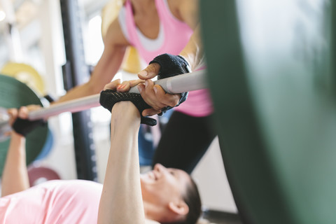 Zwei Frauen beim Langhantelbankdrücken in einem Power Rack, lizenzfreies Stockfoto