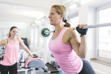 Frau macht gewichtete Rückenstrecker im Fitnessstudio - MADF000741