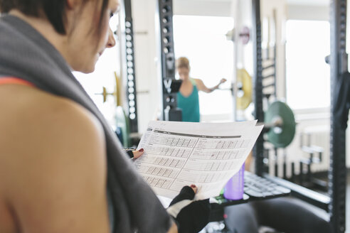 Frau überprüft ihr Trainingsprogramm im Fitnessstudio - MADF000743