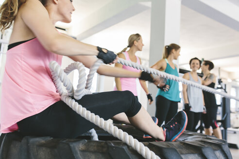 Frau zieht einen Schlitten an einem Seil im Fitnessstudio - MADF000750