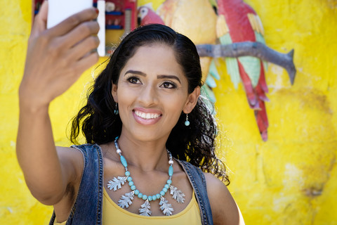 Porträt einer lächelnden Frau, die ein Selfie mit einem Smartphone macht, lizenzfreies Stockfoto