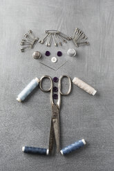 Sewing items building figur of a smiling girl on grey background - MYF001250