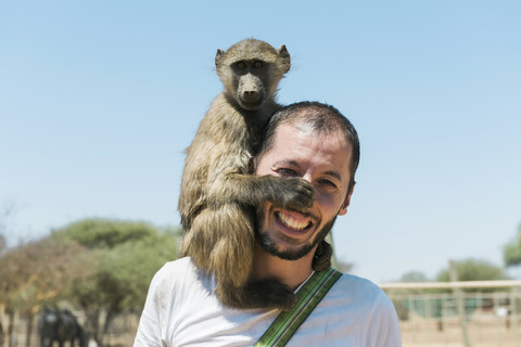 Namibia, Mann mit Pavianbaby auf der Schulter, lizenzfreies Stockfoto