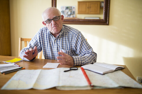 Portrait of senior man with road map planning a trip - RAEF000678