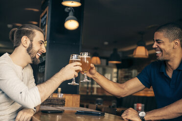 Zwei glückliche Männer in einer Bar stoßen mit Biergläsern an - ZEDF000010