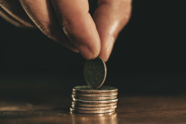 Hand holding coin on top of stack of coins - EBSF001152