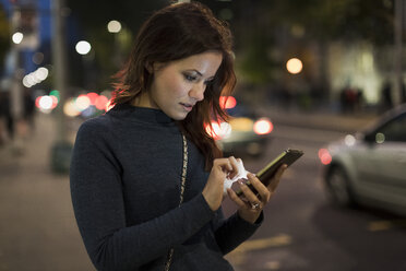 Frau überprüft ihr Smartphone am Straßenrand - MAUF000094