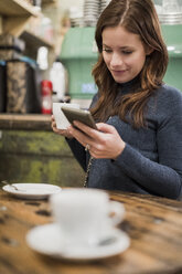 Frau überprüft ihr Smartphone in einem Café - MAUF000098