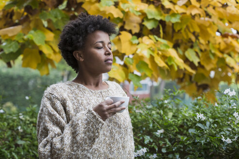 Junge Frau genießt eine Tasse Kaffee im Freien im Herbst - MAUF000105