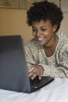 Lächelnde junge Frau zu Hause am Laptop - MAUF000107