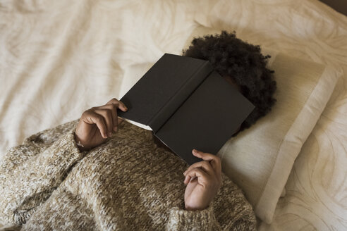 Junge Frau liegt auf dem Bett und liest ein Buch - MAUF000110