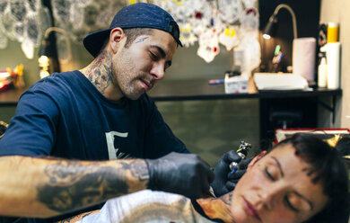 Woman receiving tattoo in tattoo studio - MGOF001095