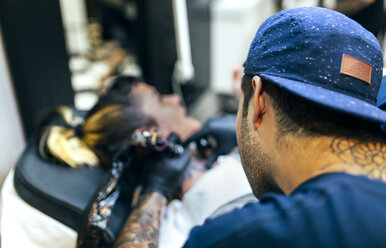 Woman receiving tattoo in tattoo studio - MGOF001097