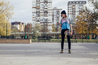 Junge Frau mit Skateboard schaut auf ihr Handy - ZEDF000019