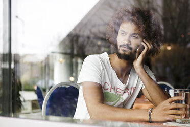 Porträt eines nachdenklichen Mannes, der in einem Café sitzt und mit seinem Smartphone telefoniert - GDF000909
