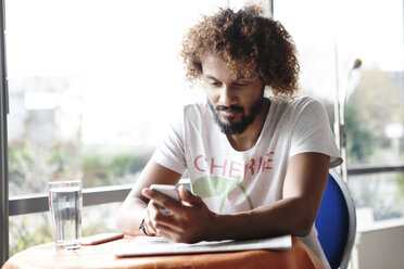 Portrait of man sitting in a cafe using smartphone - GDF000910