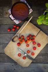 Scheiben und ganze Tomaten auf dem Schneidebrett und Kochtopf mit Tomatensuppe - LVF004206