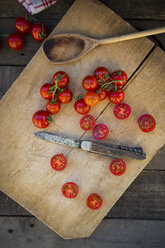 Scheiben und ganze Tomaten, Kochlöffel und ein Messer auf einem Schneidebrett - LVF004207