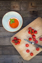 Bowl of tomato cream soup and chopping board with whole and sliced tomatoes - LVF004211