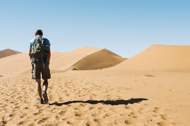 Namibia, Namib Desert, man with backpack walking through the dunes - GEMF000506