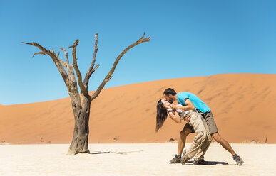 Namibia, Namib-Wüste, glückliches Paar küsst sich neben einem toten Baum im Deadvlei - GEMF000518