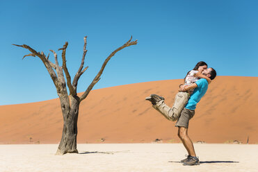 Namibia, Namib-Wüste, glückliches Paar küsst sich neben einem toten Baum im Deadvlei - GEMF000519