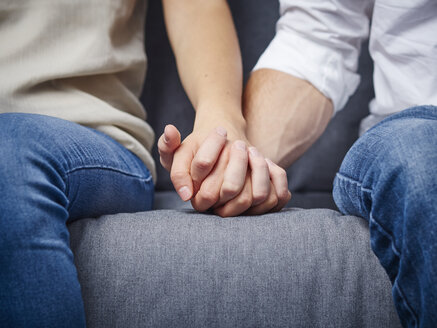 Partial view of couple holding hands on couch - DISF002261