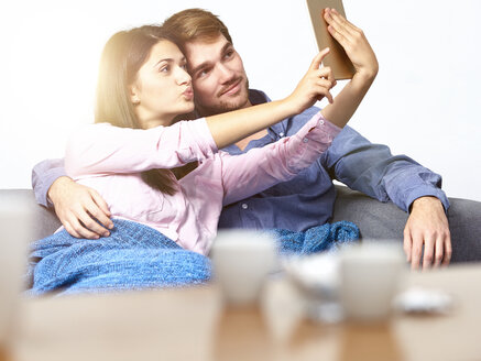 Junges Paar auf der Couch nimmt Selfie mit digitalen Tablet - DISF002265