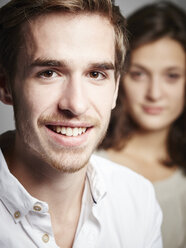 Portrait of smiling young man with girlfriend in background - DISF002269