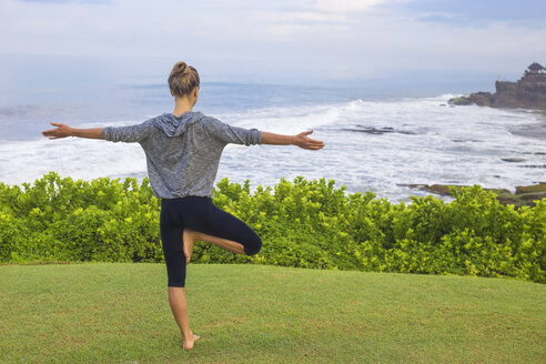 Indonesien, Bali, Tanah Lot, Frau übt Yoga an der Küste - KNTF000185